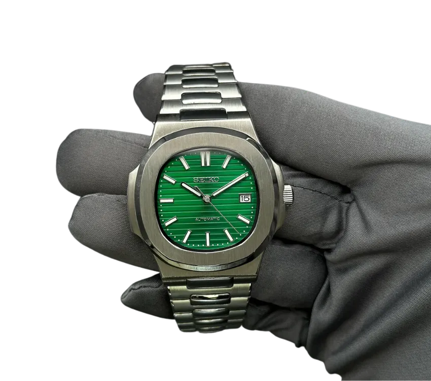 Montre automatique Seiko avec cadran vert rayé, bracelet en acier inoxydable, tenue dans une main gantée.