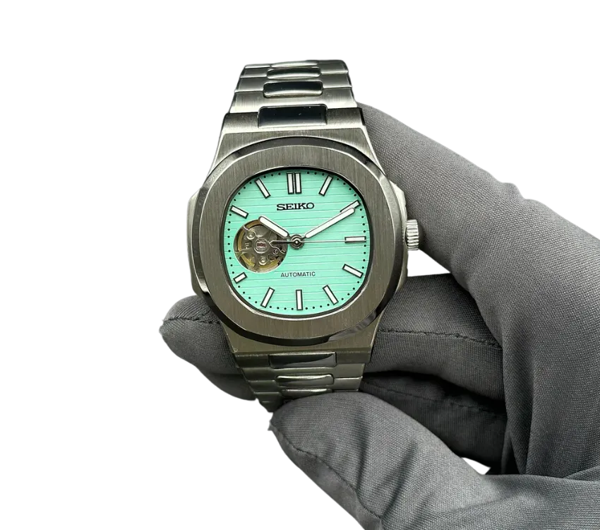 Montre automatique Seiko avec cadran turquoise et ouverture squelettée, bracelet en acier inoxydable, tenue par une main gantée.