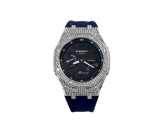 Montre Casio G-Shock élégante avec boîtier serti de cristaux scintillants, cadran noir fonctionnel et bracelet en silicone bleu foncé pour une allure moderne et robuste.