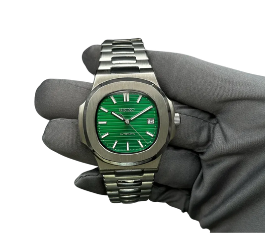Montre automatique Seiko avec cadran vert rayé, bracelet en acier inoxydable, tenue dans une main gantée.