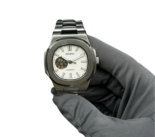 Montre automatique Seiko avec cadran blanc, design moderne en acier inoxydable, tenue dans une main gantée.