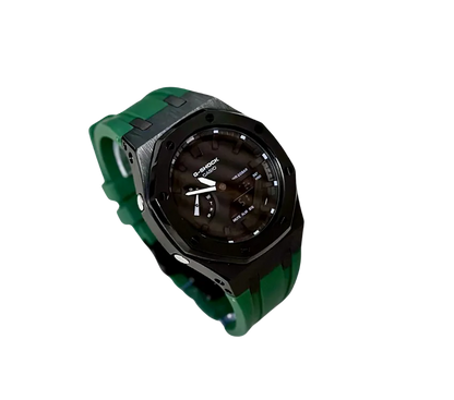  Montre Casio G-Shock avec cadran noir brillant, boîtier en métal noir mat et bracelet en silicone vert, offrant un design robuste et sophistiqué pour les amateurs de montres modernes.