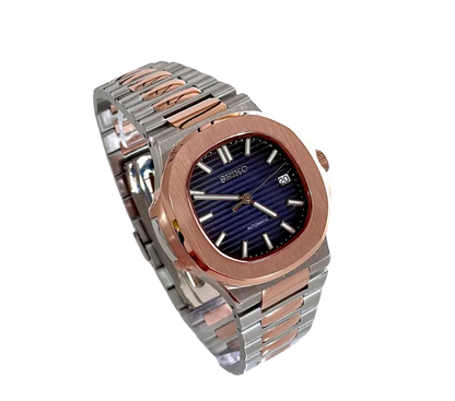 Montre Seiko automatique vue en angle, avec un cadran bleu profond texturé, boîtier en acier inoxydable et lunette en or rose, bracelet bicolore en acier inoxydable et or rose, et affichage de la date.